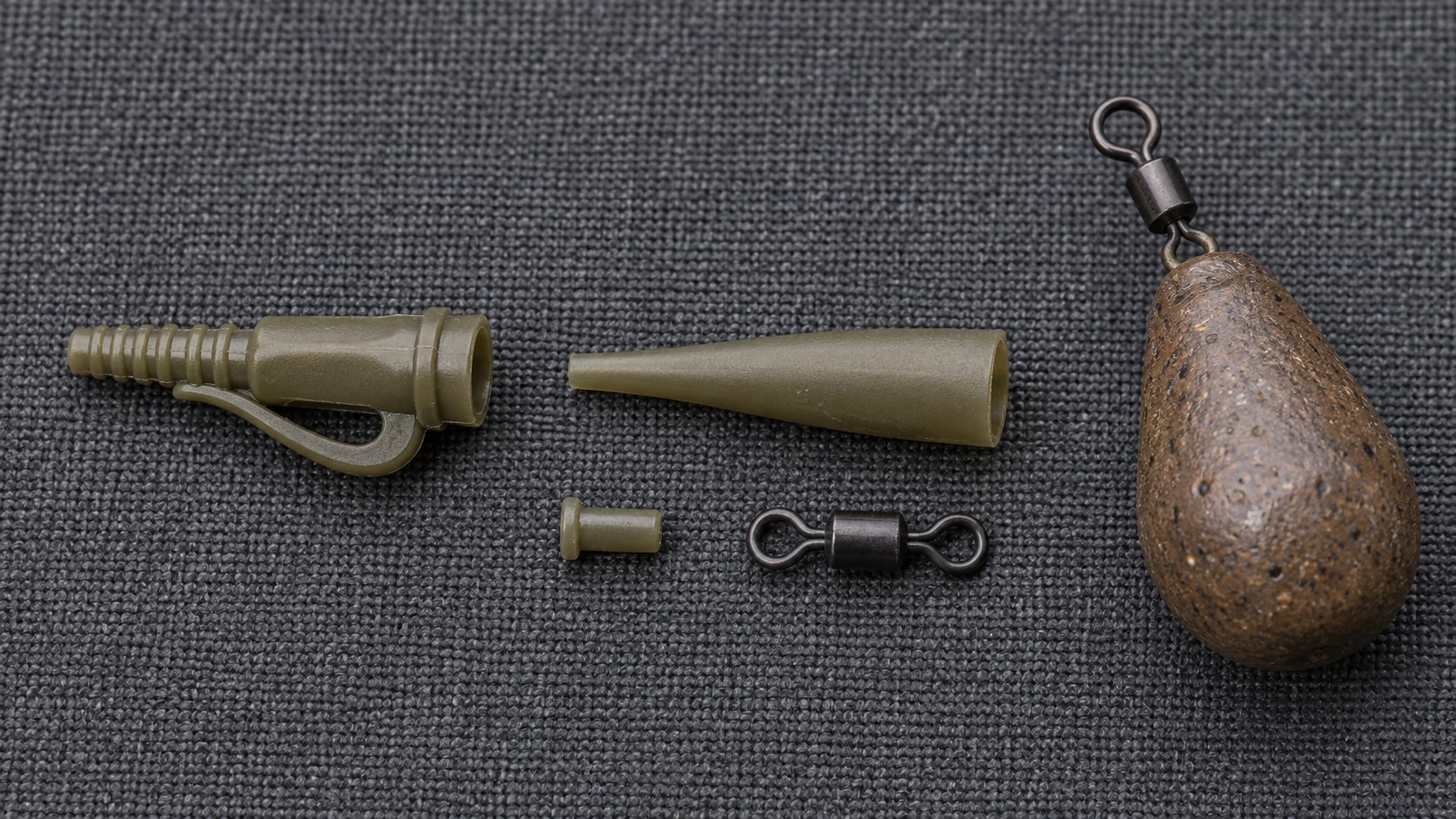 Lose Einzelteile eines Lead-Clip-Systems: Clip, Tail Rubber, Sicherungsstift, Wirbel und Birnenblei